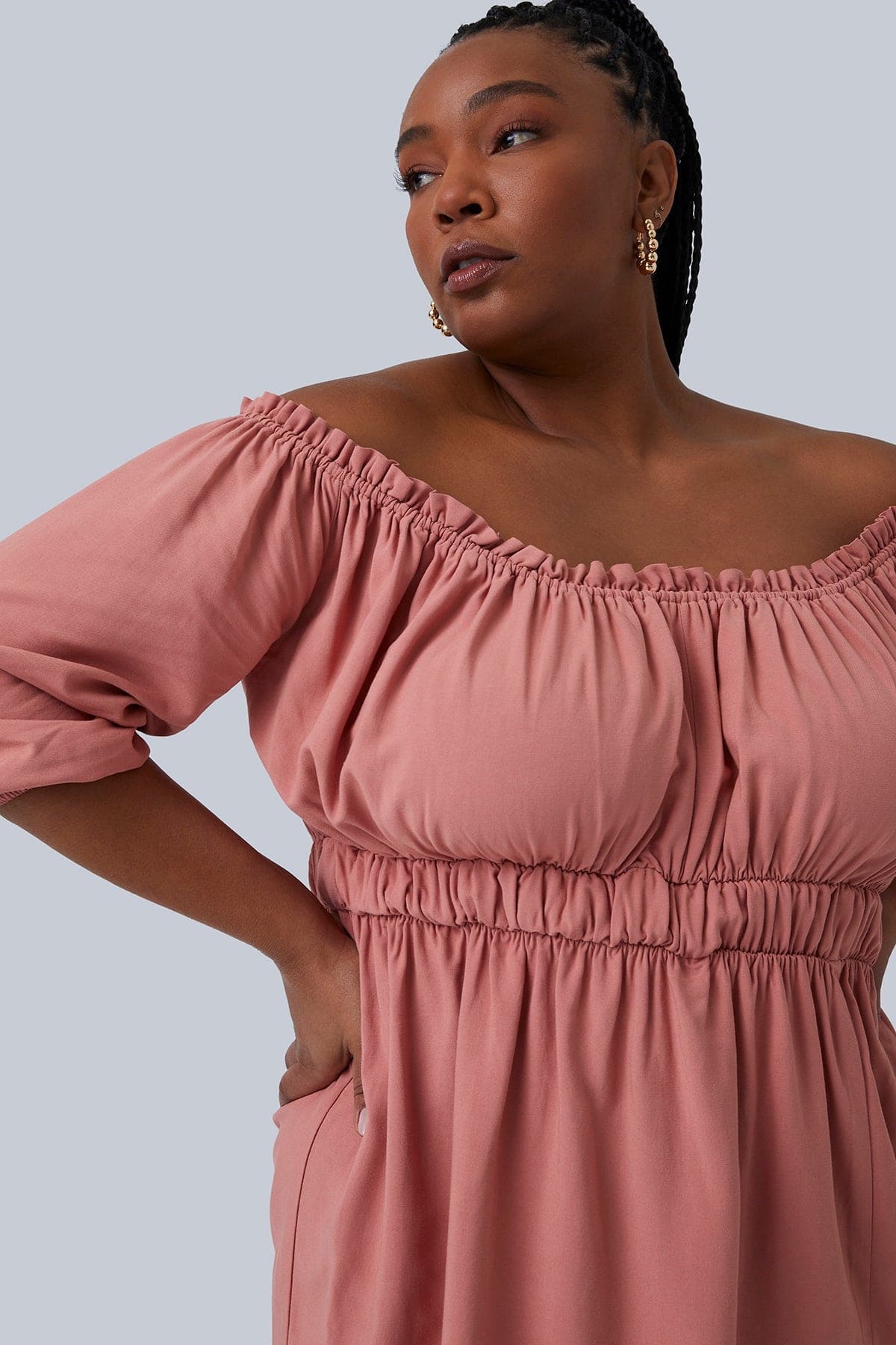 Close up shoulder shot of the Gianna Mini Dress. Model's shoulders are shrugged with hands on hips looking to the side. Sleeves are right below the elbow, color blush and size 1X. Shop Gia IRL Plus Size Boutique.