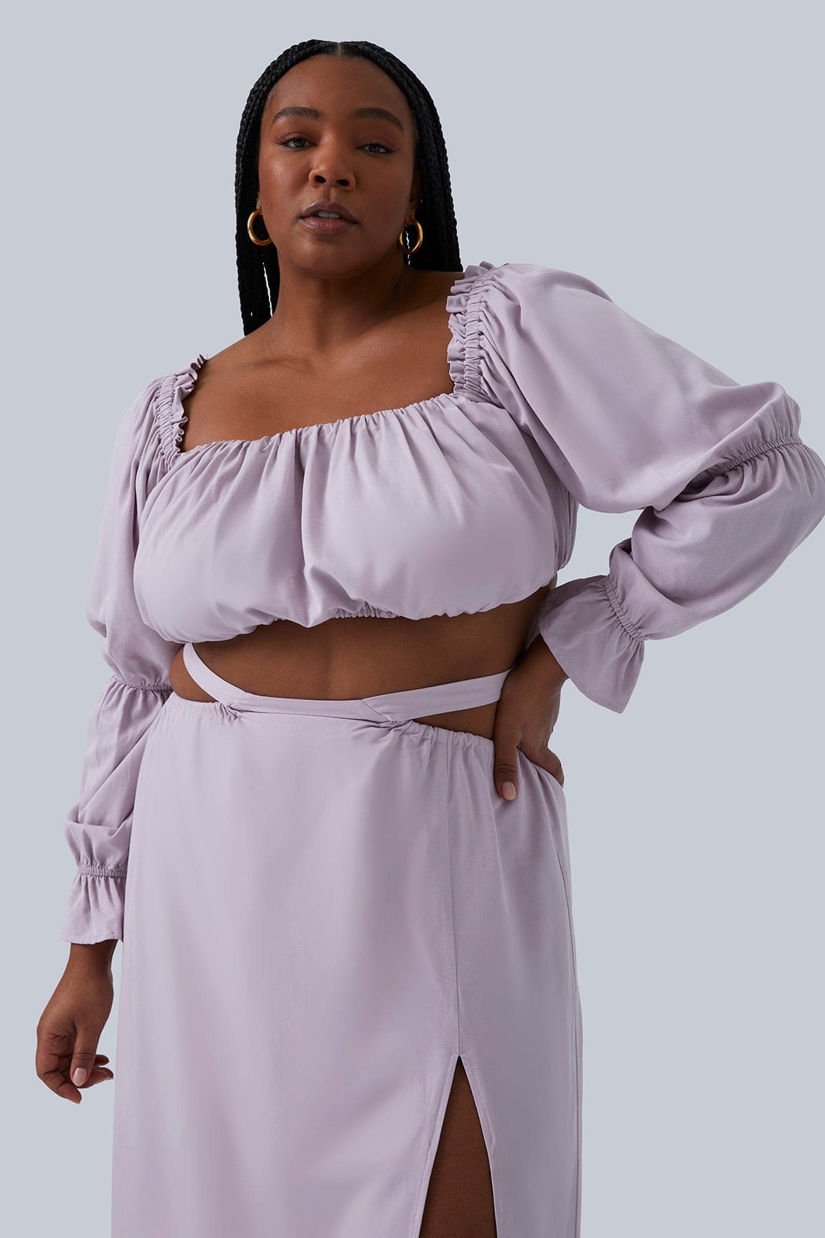 Close up of model wearing the Gia Skirt in lilac size 2X.  Top of the slit and the detail at the waist of the skirt. Models hand on hip. Full set designed by Gia IRL Plus Size Boutique.