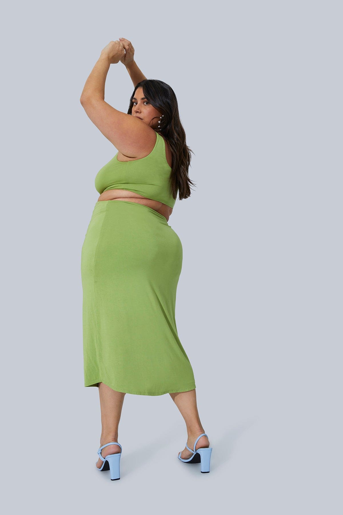CEO and Founder of Gia IRL, Gia Sinatra Plus Size Model, posing from behind in Gigi Midi Dress size 1X. Dress is in Pistachio color and is paired with light blue strappy heels.