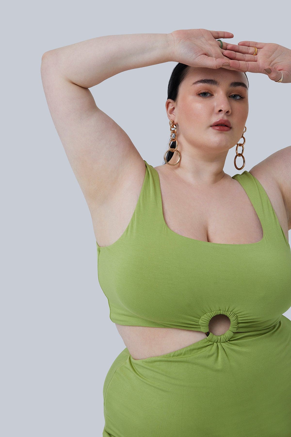 Detail shot of Gigi Midi Dress in Pistachio with the cut out sides on this plus size dress. Dress worn by plus size model with dark hair in low pony tail. Hands resting on forehead.