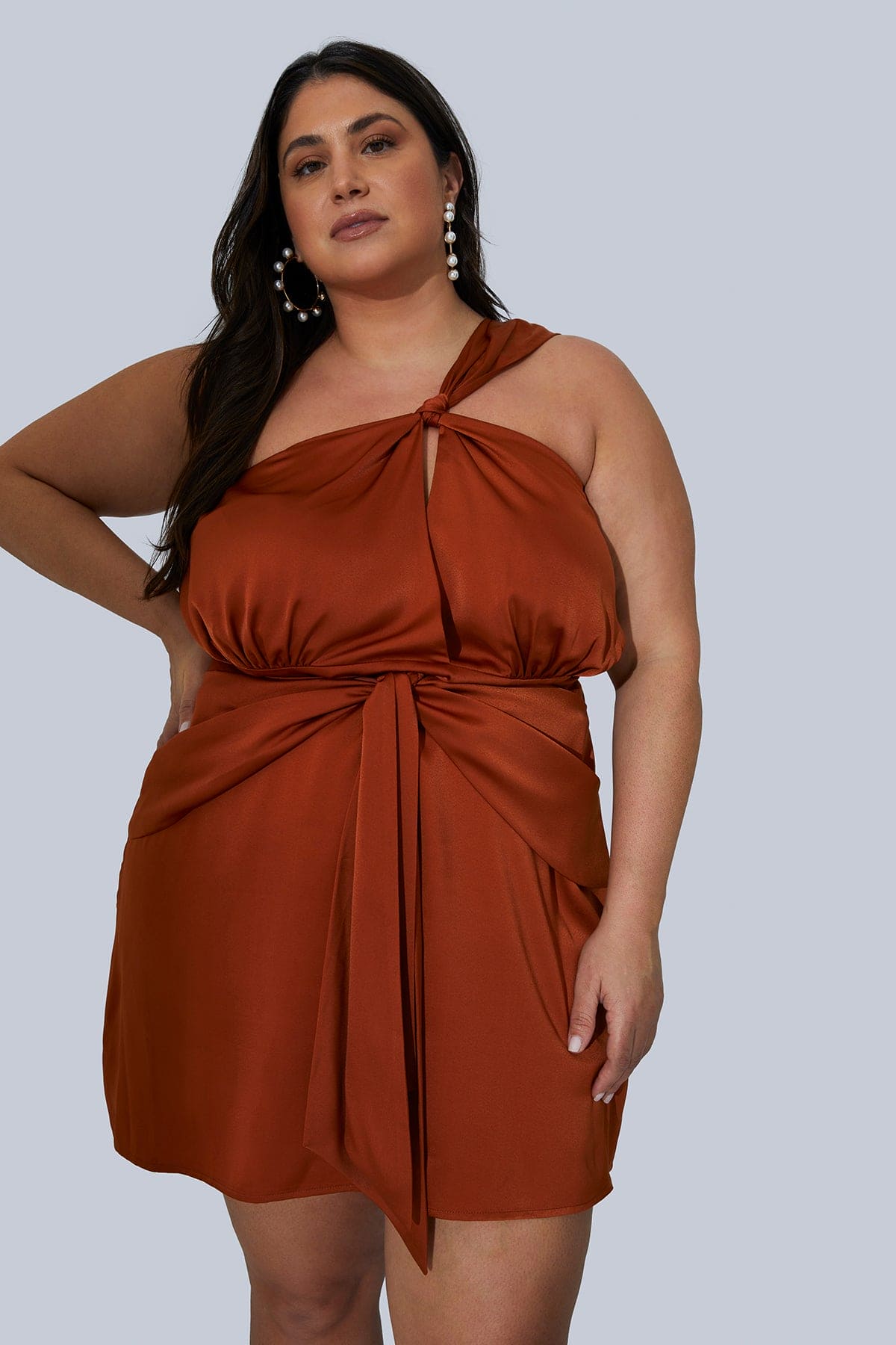 CEO and Founder of Gia IRL, Gia Sinatra, in the Maya Mini Silk Dress size 16 in Rust for Plus Size Women. Front view with hand on hip.